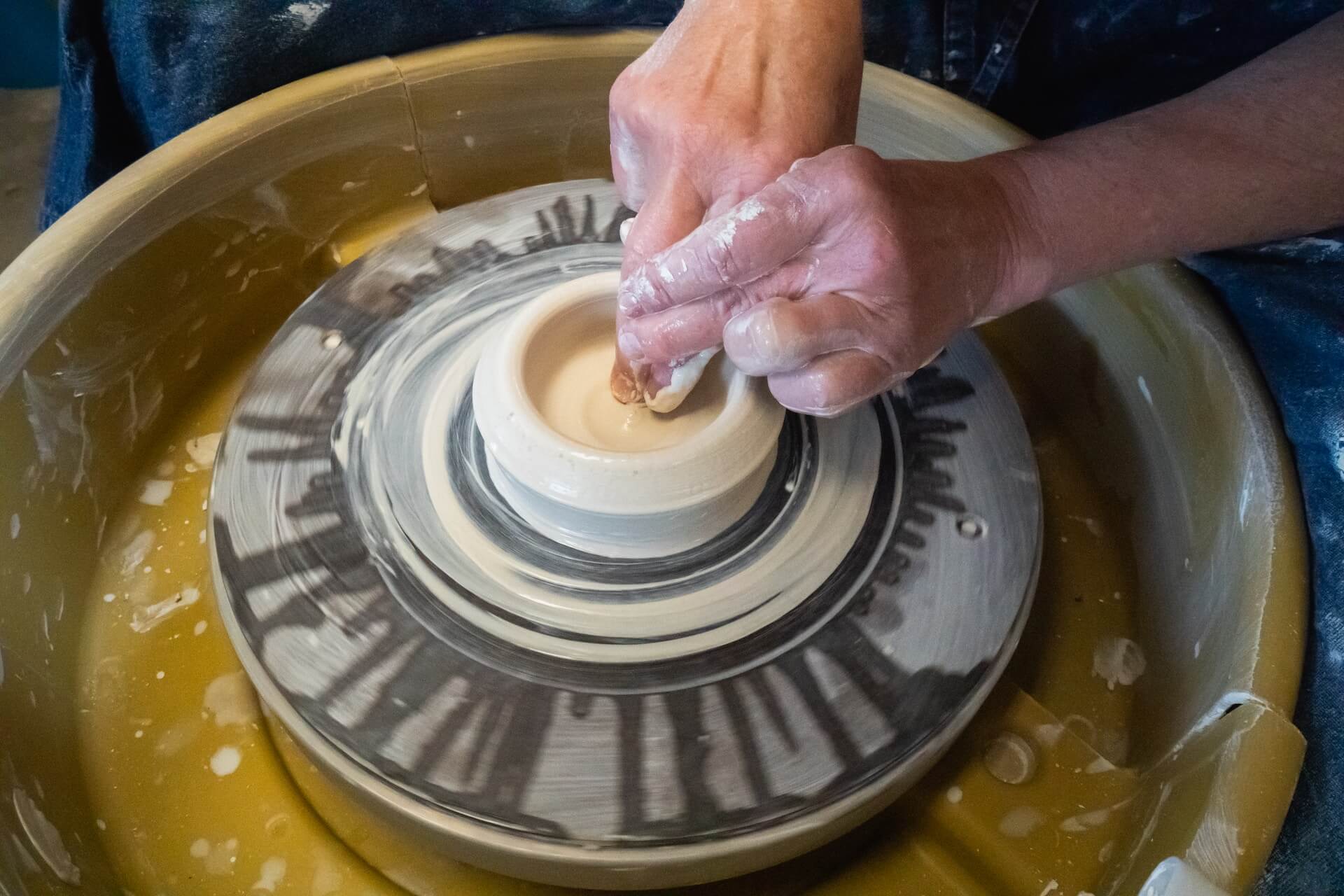 Person using pottery wheel and hands to making ceramic bowl