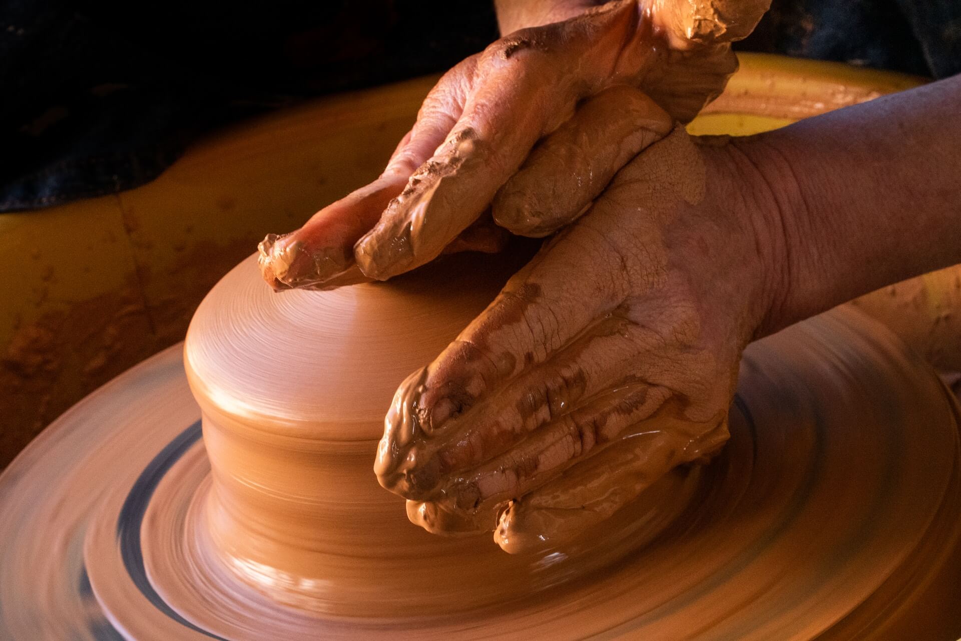 Person using pottery wheel and hands to making ceramic bowl